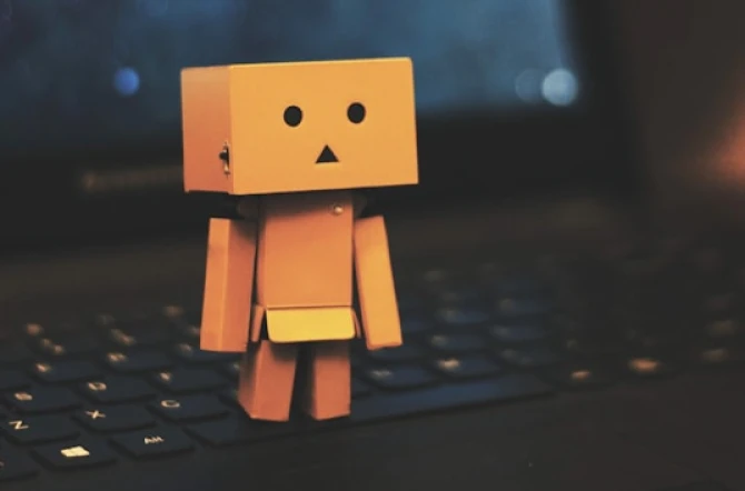 Computer pixel character in yellow with surprised face standing on laptop keyboard